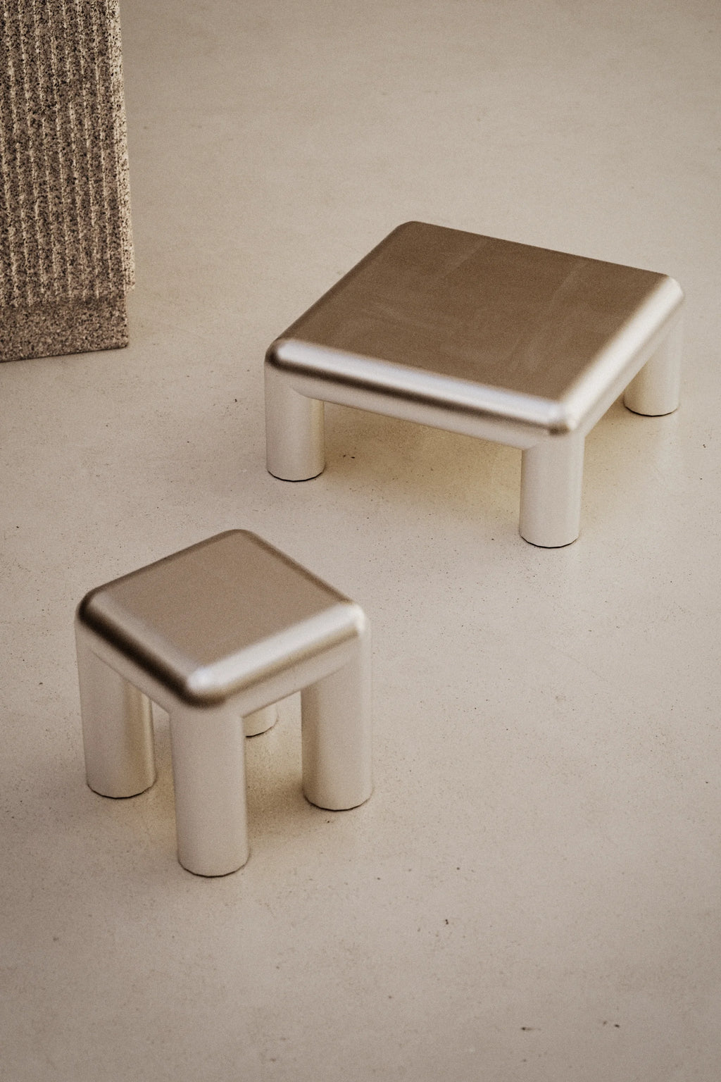 Two metallic stools on a neutral surface