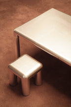Metallic stool and table on a brown surface