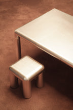 Metallic stool and table on a brown surface