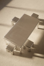 Metallic dining table with four chairs on a beige surface