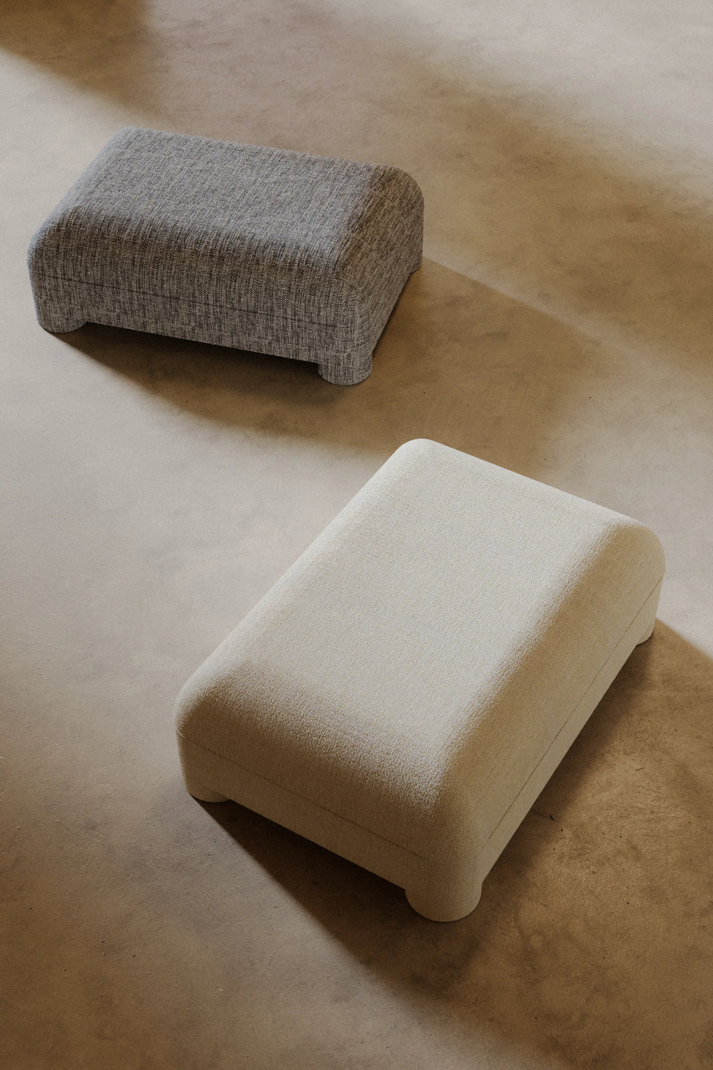 Two rectangular cushions, one gray and one beige, on a wooden floor.