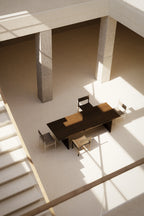 Modern office space with a large desk and chairs in a minimalistic setting.