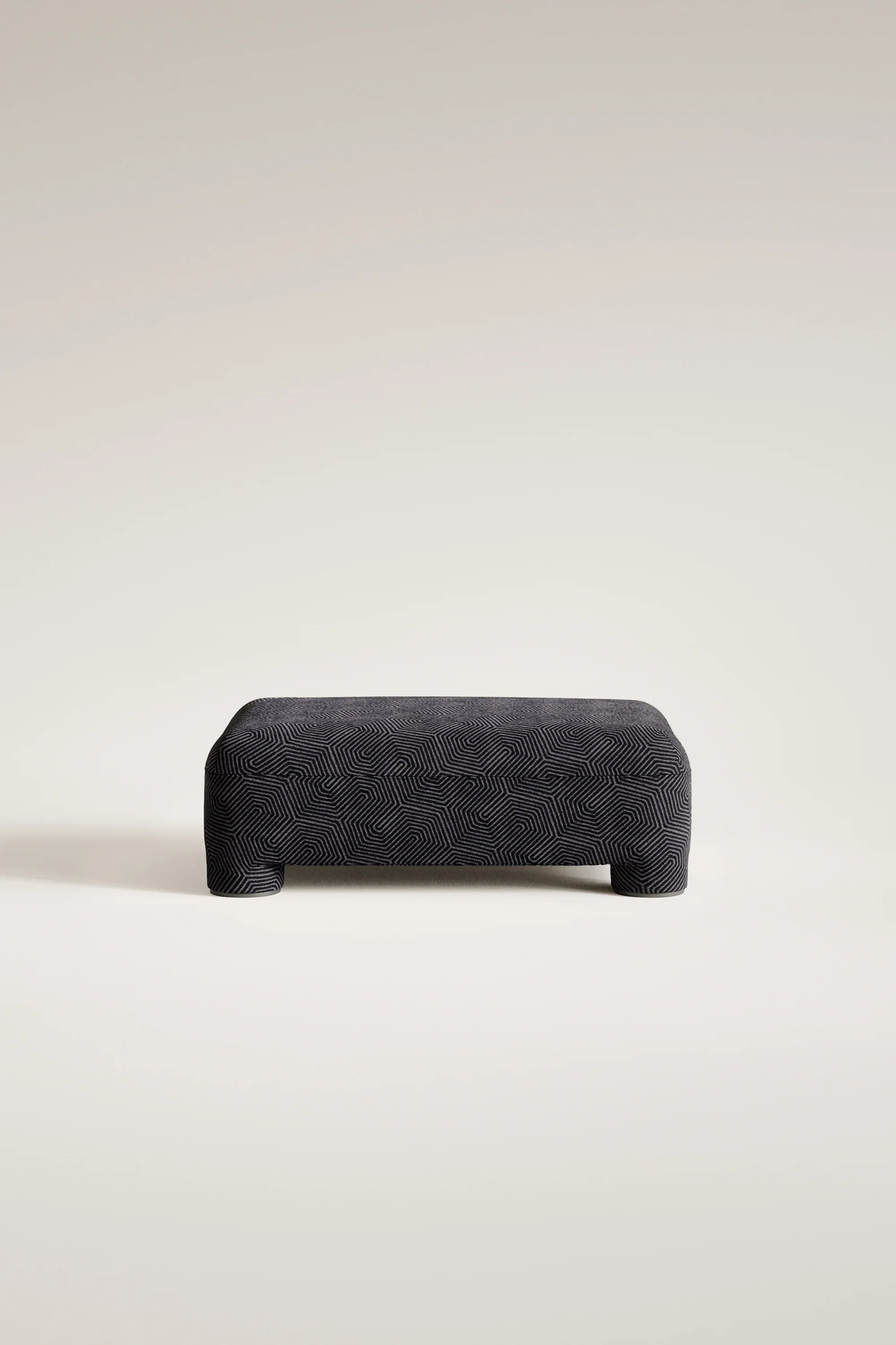 Dark gray textured ottoman on a light beige background