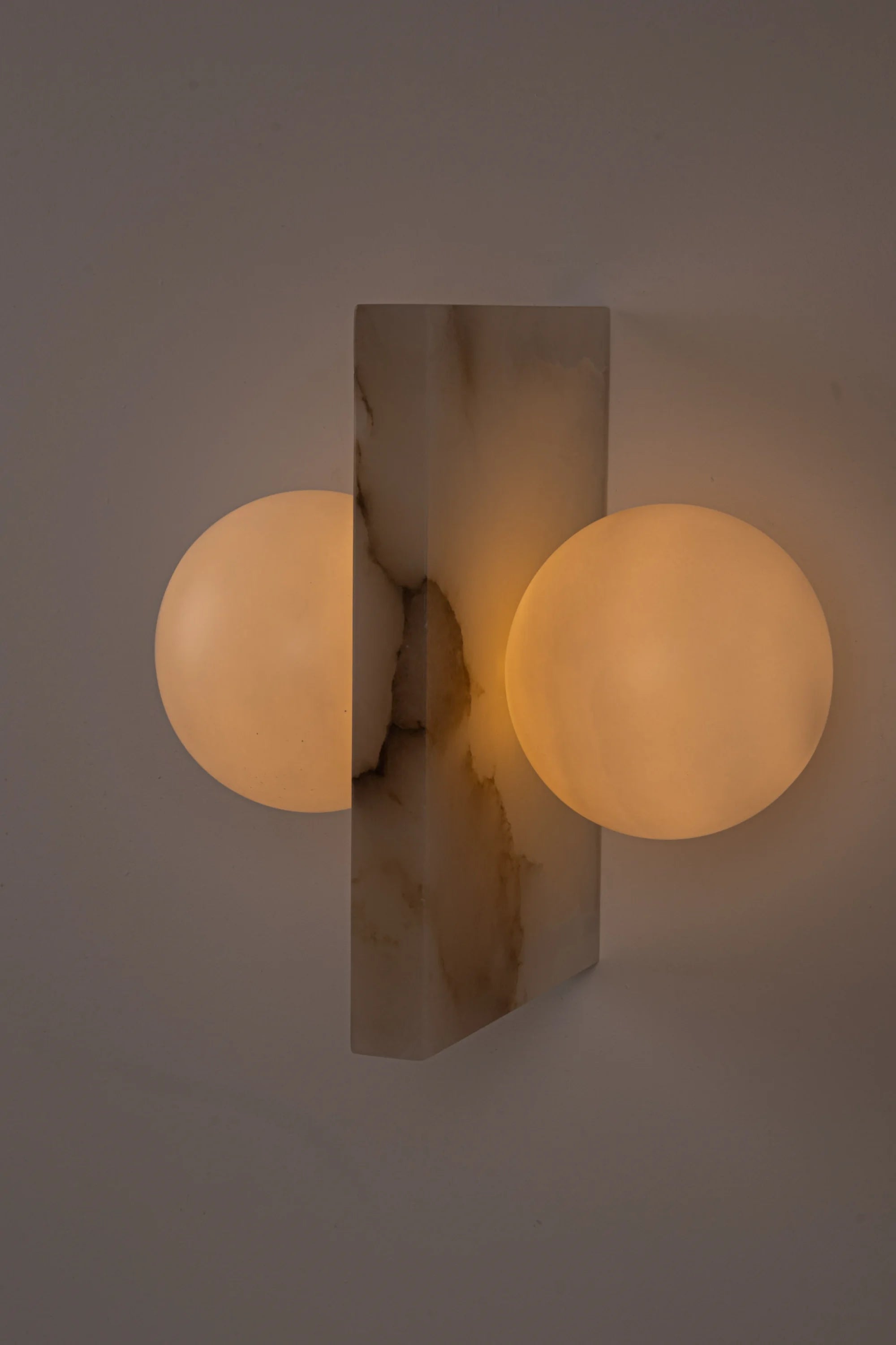 Wall-mounted light fixture with two spherical bulbs on a neutral background