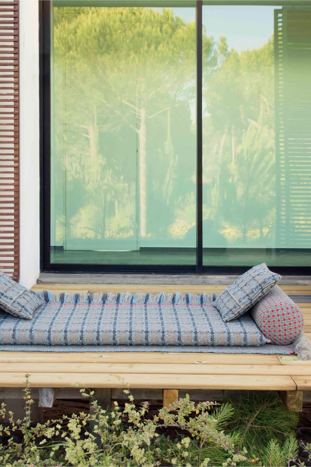GAN Rugs Garden Layers Composition 06, a boho outdoor sofa featuring a large rectangular woven outdoor mattress in blue-grey and beige tones with a fringed edge.