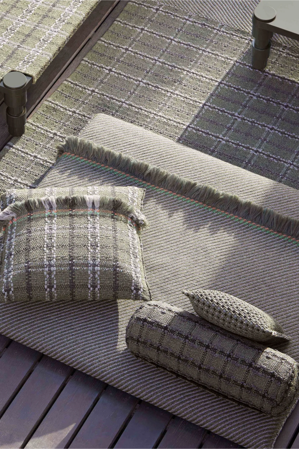 GAN Rugs Garden Layers Composition 04, a contemporary outdoor lounge set featuring a large ribbed olive green outdoor rug with a fringed edge and subtle colorful accents.