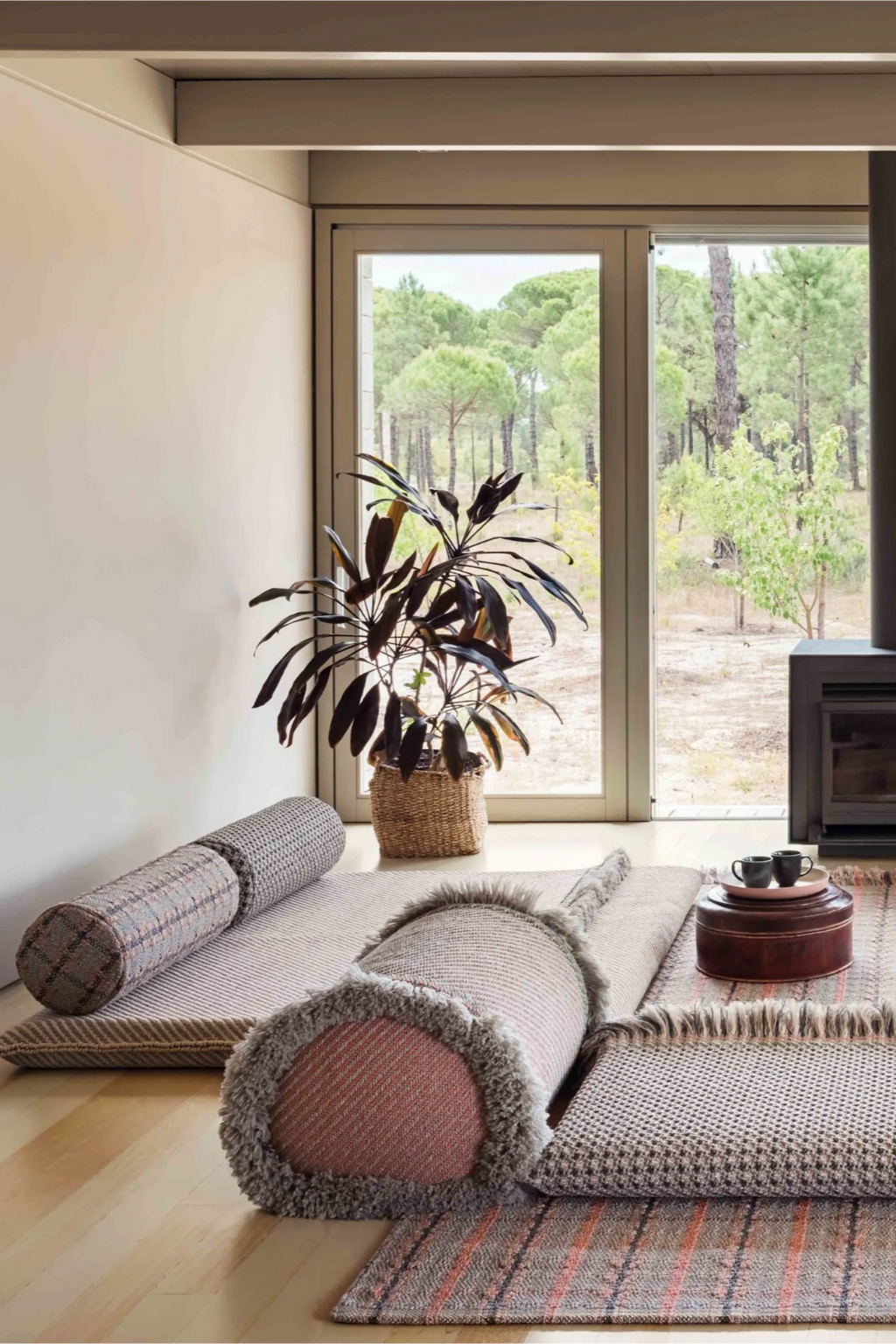 GAN Rugs Garden Layers Gofre Small Roll in a subtle terracotta and beige palette, showcasing a textured, woven pattern. This versatile, elegant roll is presented on a light wooden floor, enhancing a serene indoor-outdoor living area with natural light.