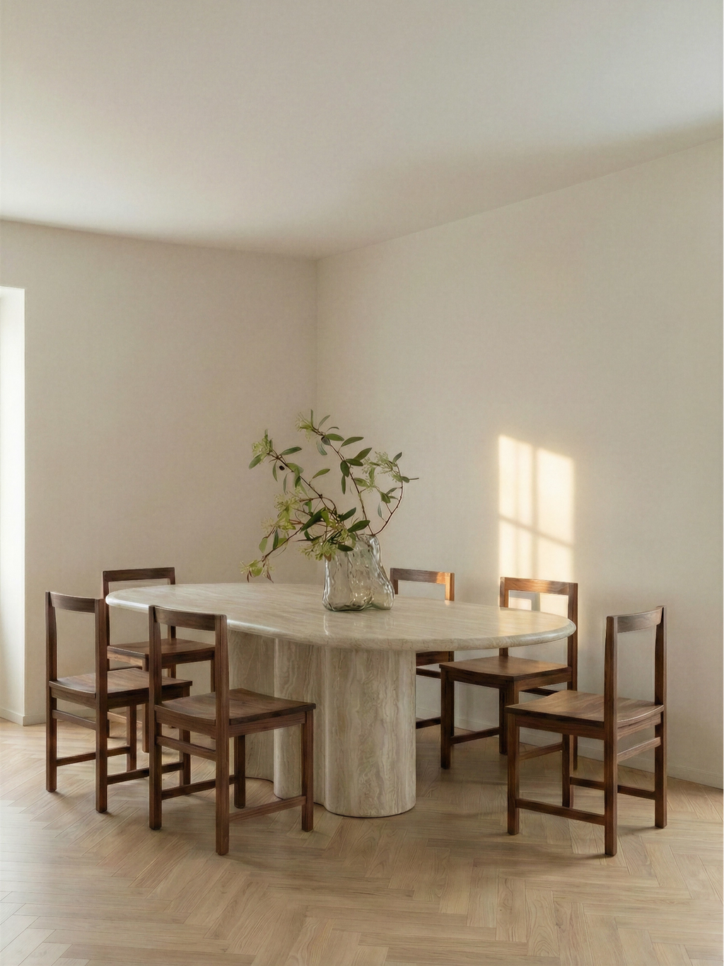 TCL Studios Galatea Travertine Dining Table, a stunning oval dining table crafted from natural light beige travertine with a smooth polished finish and unique veining, supported by a substantial cylindrical pedestal base. This organic modern and minimalist travertine table is perfect for contemporary dining rooms or luxurious, design-conscious interiors seeking a natural stone centerpiece.