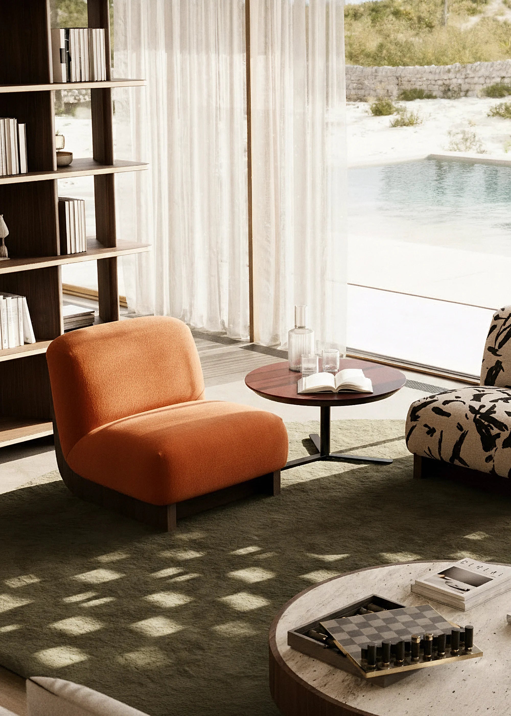 Modern living room with an orange velvet armchair, round coffee table, and bookshelf.