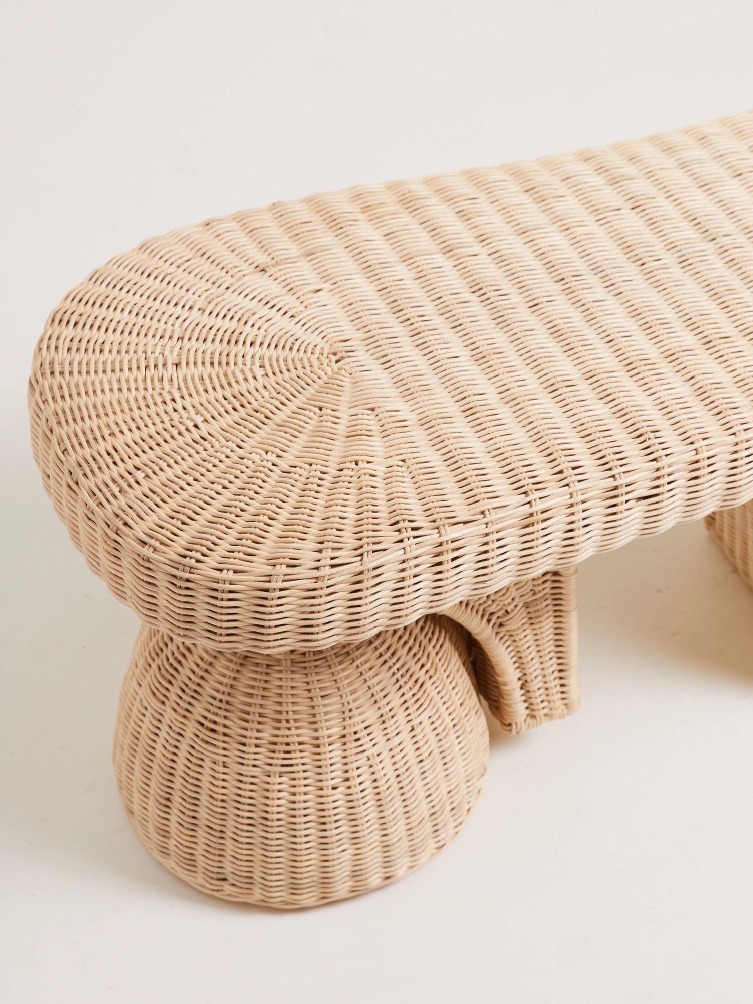 Heaps & Woods Alfred Bench, a light natural rattan bench featuring an elongated oval top with a distinct ribbed weave pattern and two sculptural, bulbous bases crafted from intricately woven natural fibers. This organic modern bench offers versatile accent seating for coastal living rooms, boho bedrooms, or inviting entryways.