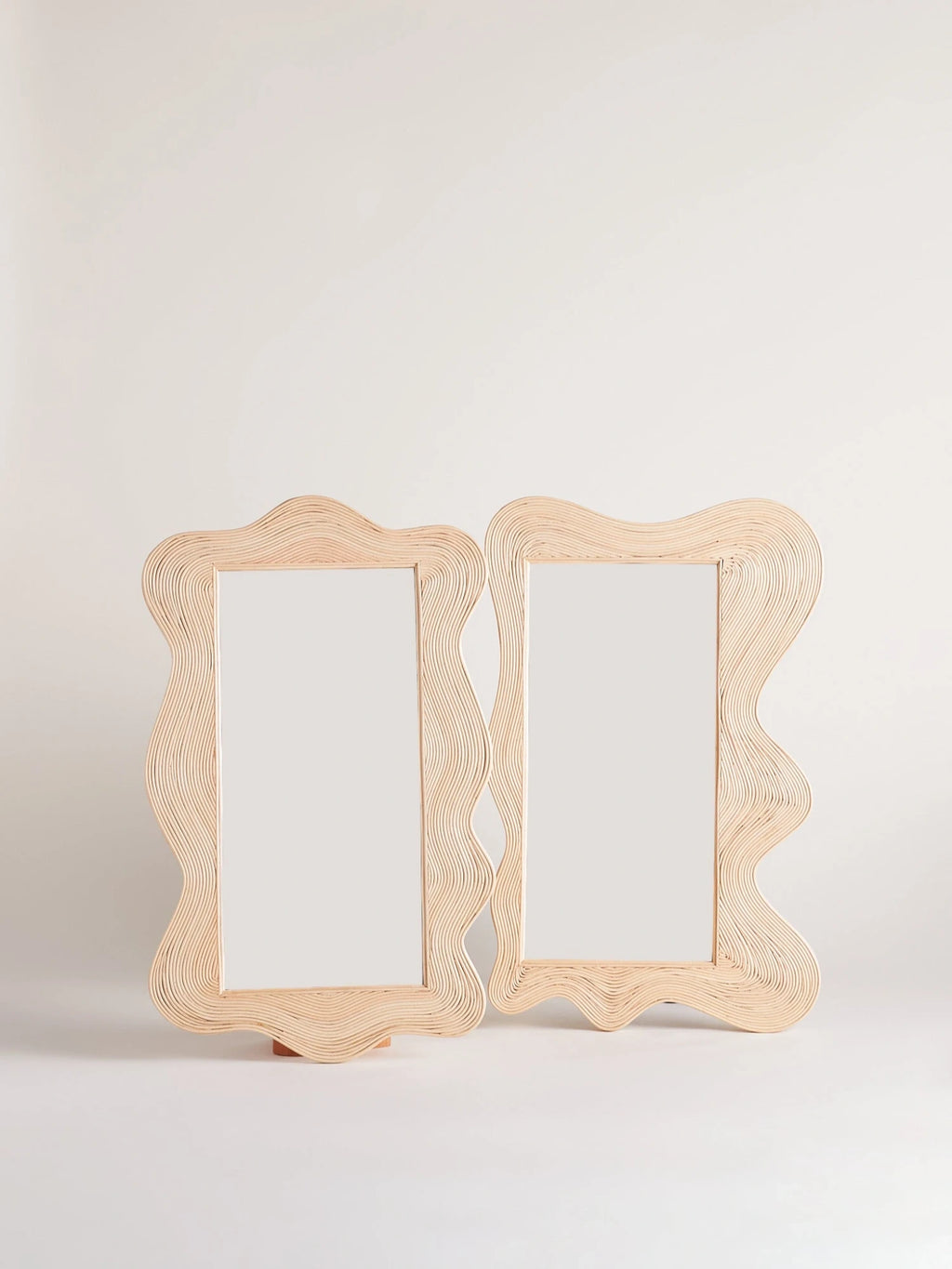 Heaps & Woods Sofia Mirror, an organic modern decorative mirror featuring a unique, undulating frame meticulously crafted from natural light rattan, creating a distinct layered and ribbed texture.