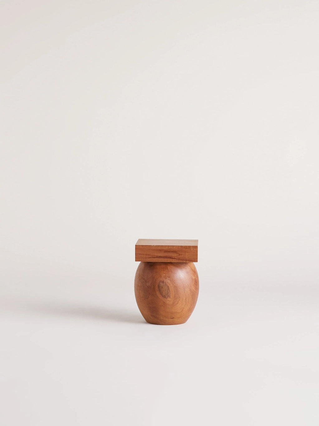 Heaps & Woods Valentina Stool, a solid wood accent piece showcasing a smooth, rounded spherical base in warm natural brown tones, contrasted with a clean, flat square top. This organic modern design highlights the rich grain of the natural wood, creating a sculptural and minimalist silhouette. Ideal as a versatile side table, small stool, or plant stand for contemporary living rooms, bedrooms, or entryways.