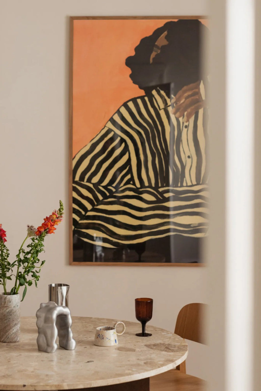 The Poster Club Serene Stripes, a contemporary abstract figurative art print featuring a person in a bold black and pale yellow striped shirt against a warm terracotta orange background. This graphic wall art is presented in a natural oak wood frame, perfect as a striking focal point for modern minimalist or contemporary living rooms and gallery walls.