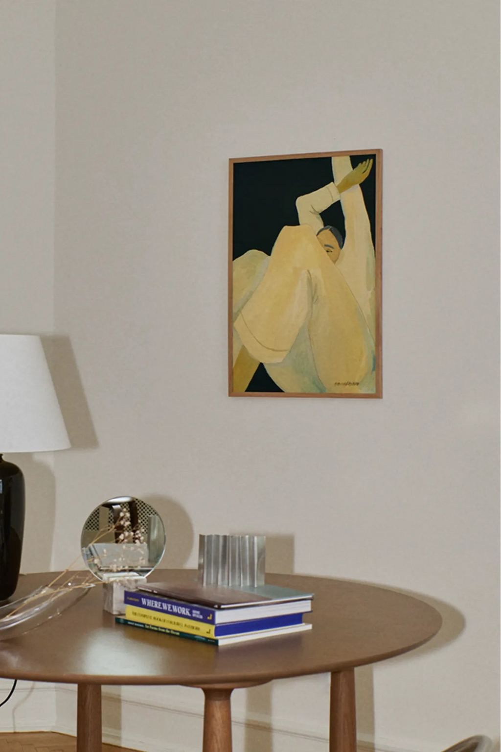 The Poster Club The Dream, an abstract figurative art print featuring a relaxed, reclining person rendered in soft cream and pale yellow hues with subtle blue accents, set against a rich, deep black background. This contemporary art piece is elegantly framed in a light natural oak wood frame. It's an ideal minimalist wall art choice for modern living rooms, Scandinavian bedrooms, or a curated gallery wall.