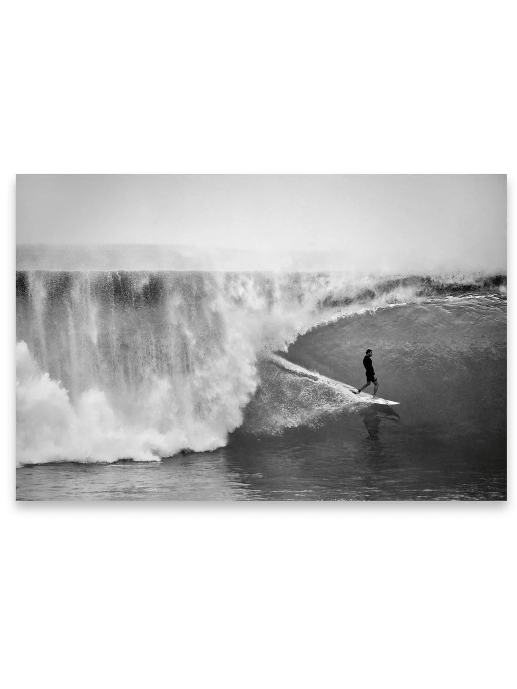 Book Hawaii, a dramatic black and white photograph capturing a surfer expertly riding a massive, powerful wave with a wall of whitewater crashing behind. This striking surfing print is perfect for coastal decor enthusiasts or adventurers seeking inspiring wall art.