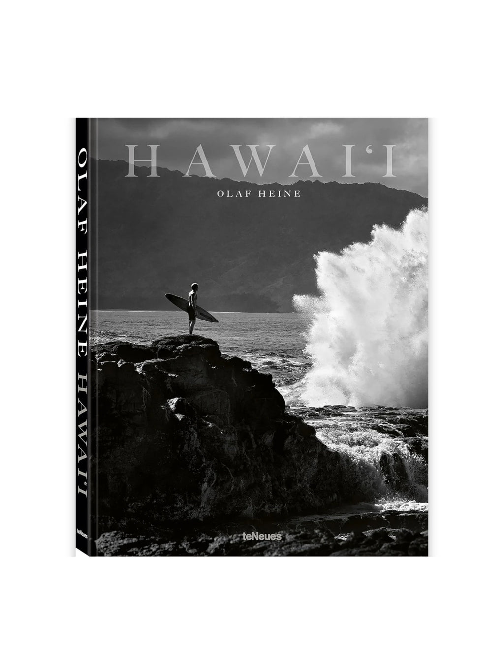 Book Hawaii, a black and white photography book featuring a surfer on a rocky Hawaiian coast with a dramatic ocean wave crashing. This premium hardcover art book is perfect for travel enthusiasts and photography collectors interested in iconic surf culture.