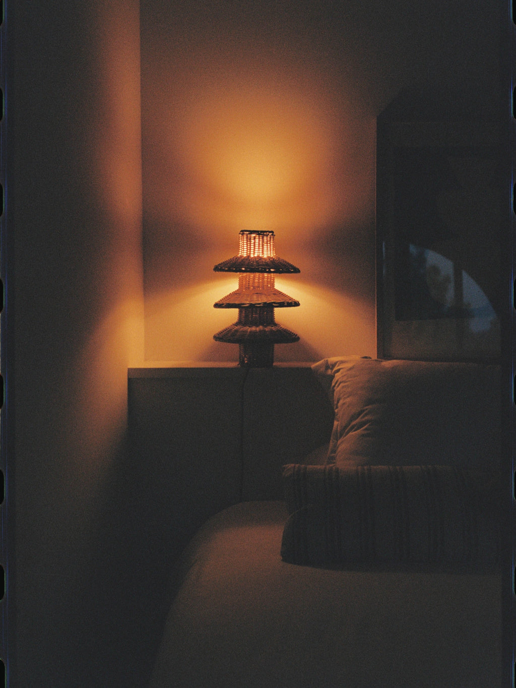 Heaps & Woods Rose Table Lamp, a warm amber-lit tiered table lamp featuring a natural hand-woven rattan shade with three stacked, conical levels, creating an organic modern pagoda-inspired silhouette.