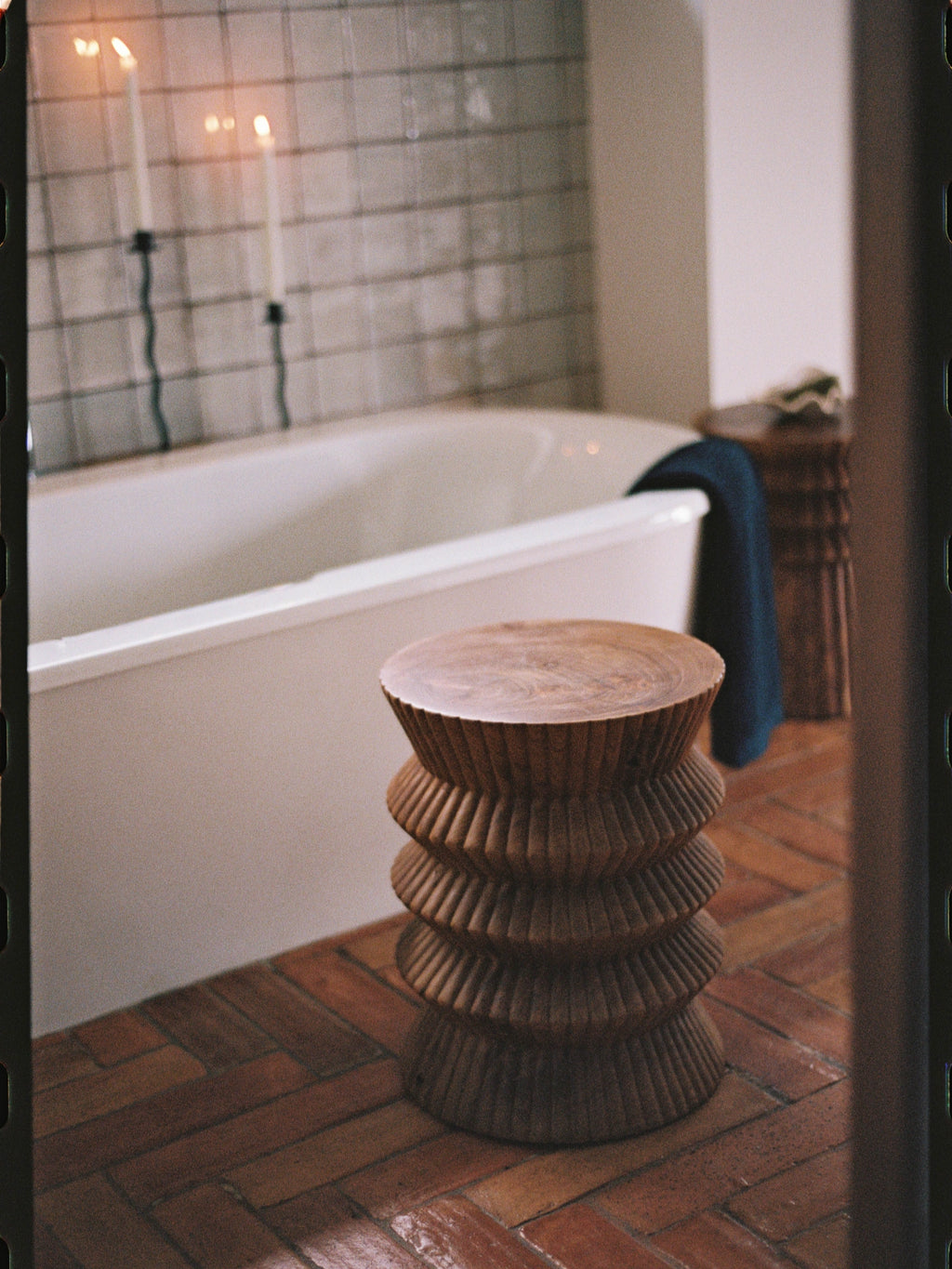 Heaps & Woods Carla Stool, a warm brown solid wood stool featuring a unique stacked, fluted, and intricately carved cylindrical design, with a smooth, flat top showcasing its natural wood grain. This organic modern accent stool is ideal as a sculptural side table or functional bathroom stool, perfect for creating a spa-like interior.