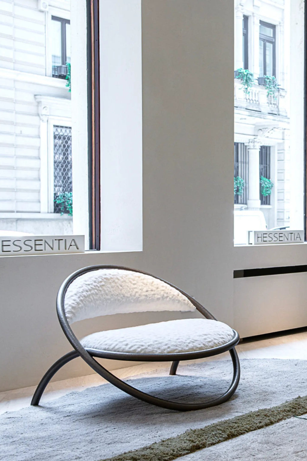 Hessentia Ryo Armchair, a striking organic modern lounge chair featuring a continuous dark metal frame that forms a sculptural silhouette, integrating the legs and armrests.