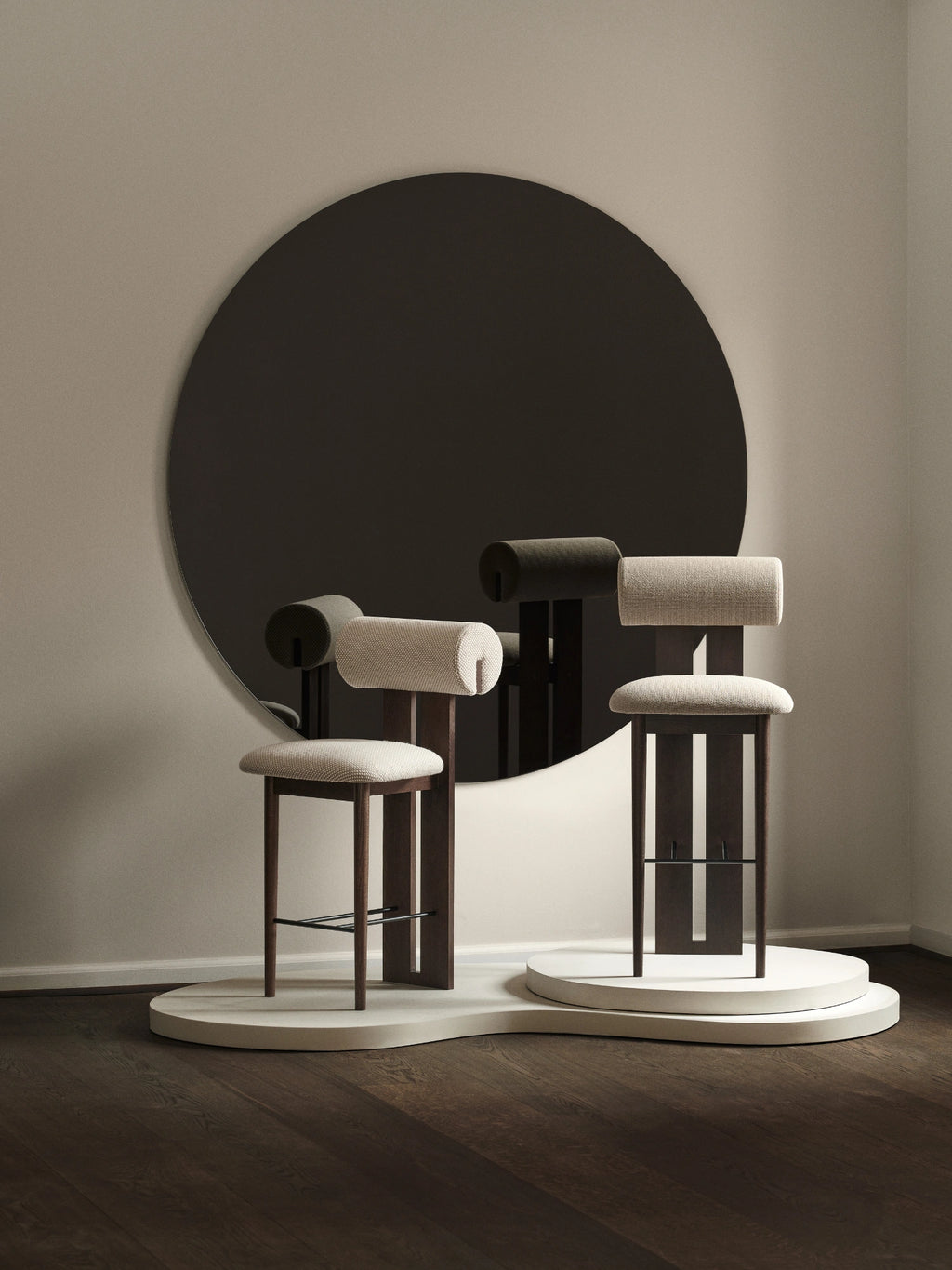 NORR11 Hippo Bar Chair, a modern minimalist bar stool featuring a dark stained solid oak frame with a unique cylindrical upholstered backrest and a light beige bouclé fabric seat.