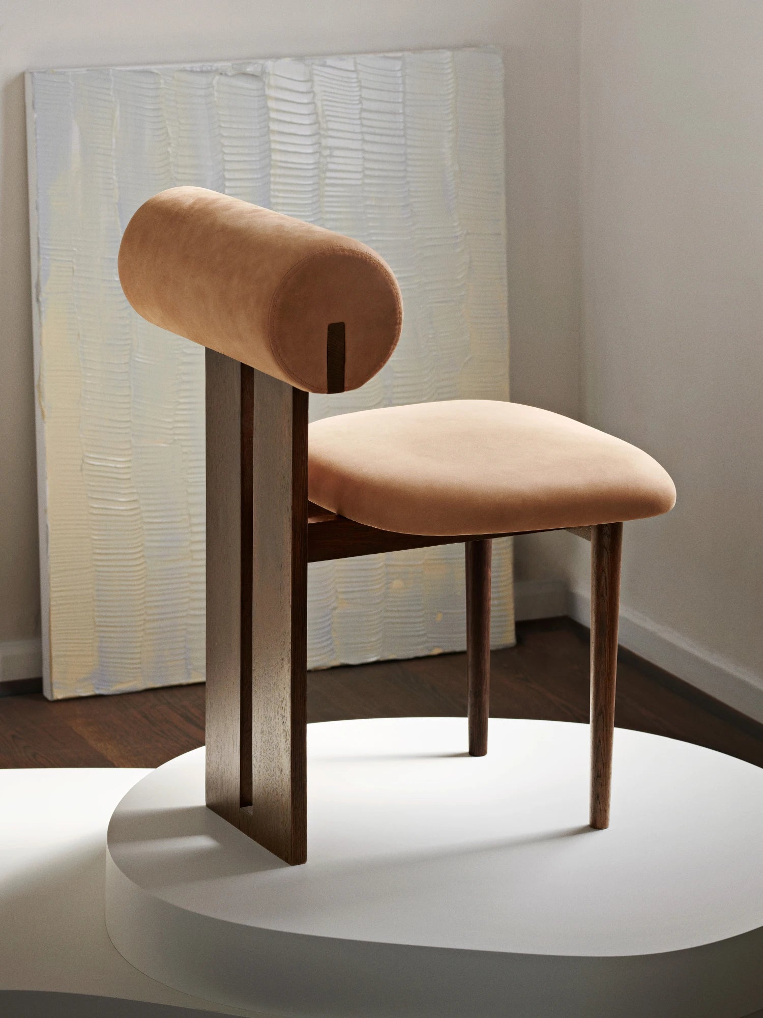 NORR11 Hippo Chair, a sculptural organic modern dining chair featuring a distinctive cylindrical backrest and a gently curved seat, both upholstered in a warm beige suede-effect fabric.