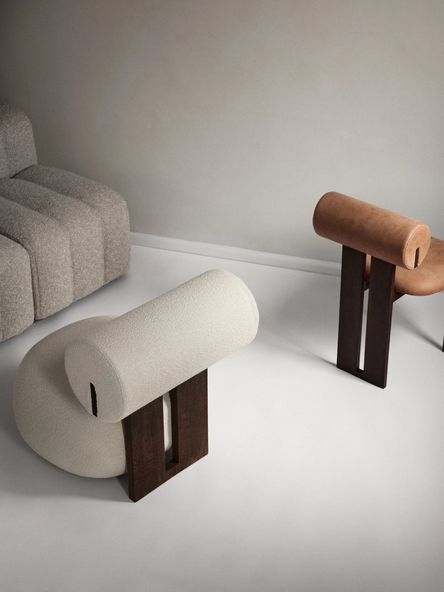 NORR11 Hippo Chair, an organic modern lounge chair with a distinctive sculptural silhouette, featuring a plush cylindrical backrest and curved seat supported by a bold dark solid wood base.