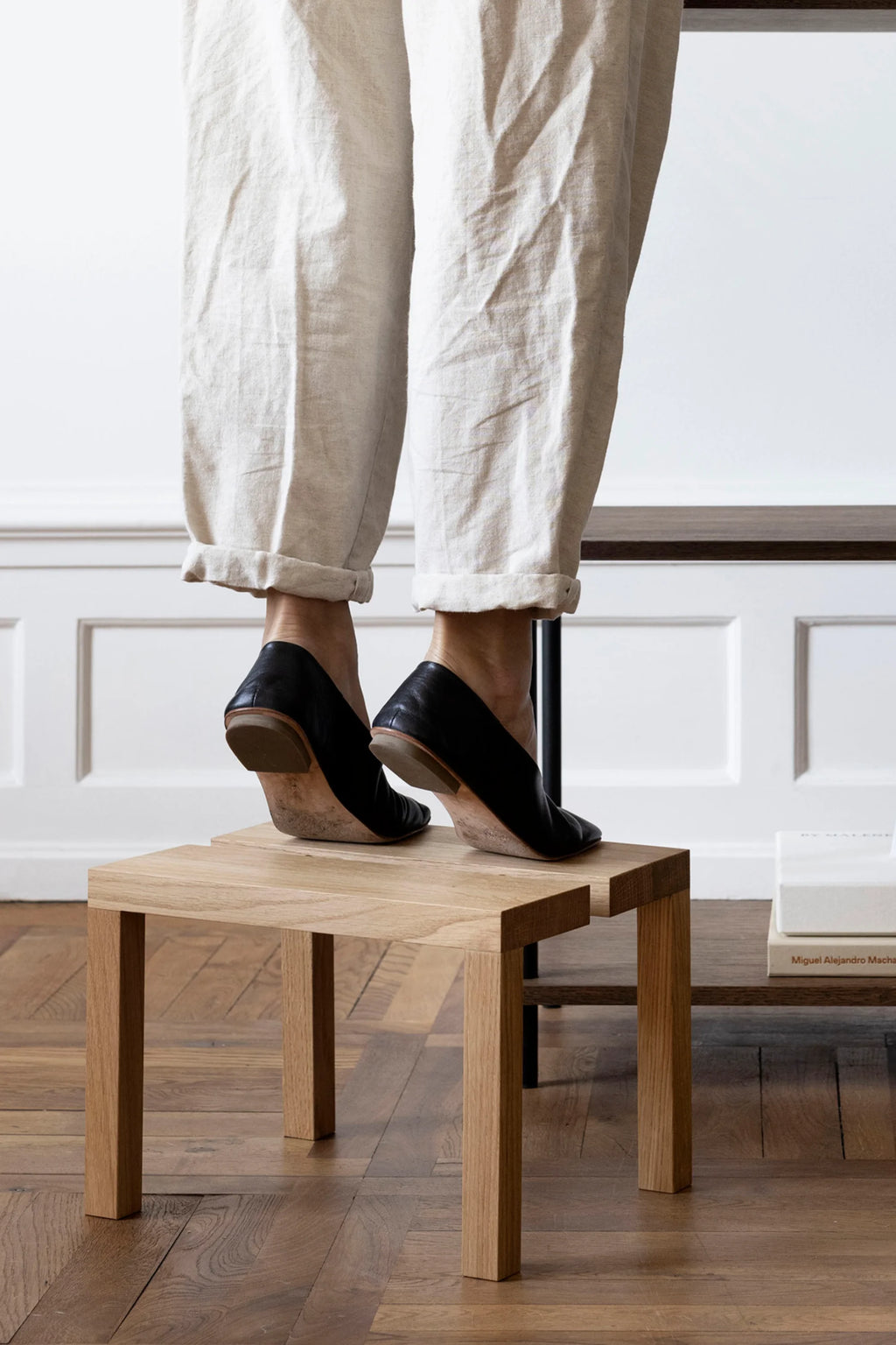 MOEBE Peg Step Stool, a modern minimalist step stool crafted from light natural solid oak wood with a distinctive geometric top featuring an interlocking design and clean, straight legs. This versatile Scandinavian wood stool is perfect for reaching high shelves in the kitchen, as a bedside table, or as an accent piece in contemporary living spaces.