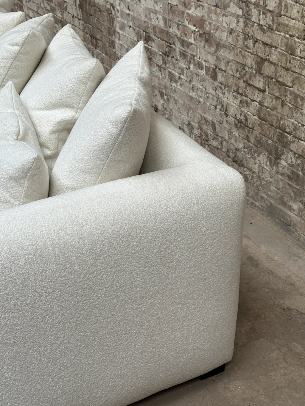 Tinted Objects Cornell Sofa, a luxurious off-white bouclé fabric sofa with plush, deep-set cushions and a contemporary, minimalist design. This elegant and comfortable seating solution is perfect for modern living rooms and cozy family spaces, appealing to those seeking stylish and inviting home decor.