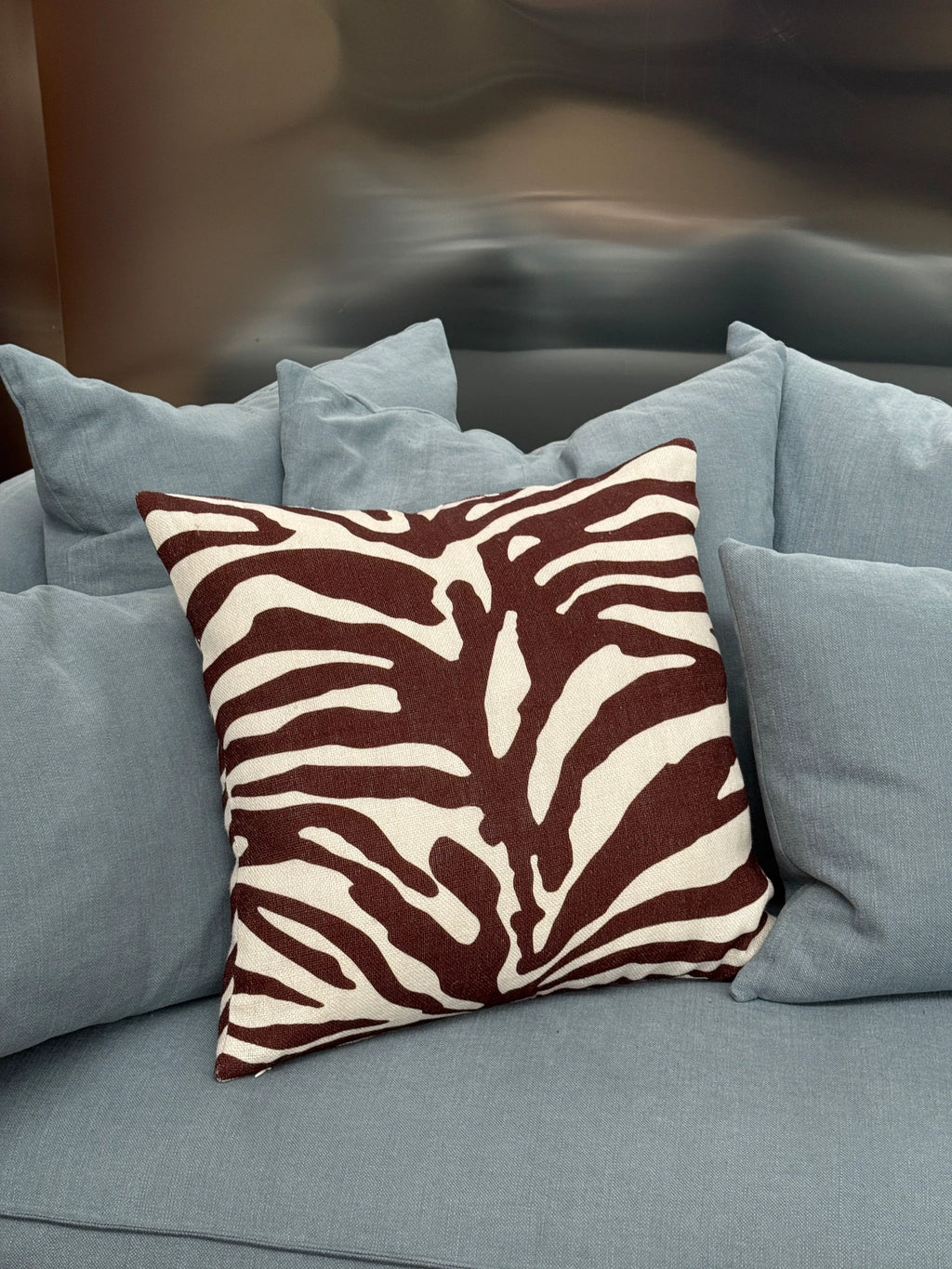 Tinted Objects Lange Throw Pillow, a stylish square cushion featuring a bold brown and cream zebra print pattern. This decorative accent pillow adds a touch of modern flair to any sofa or armchair.