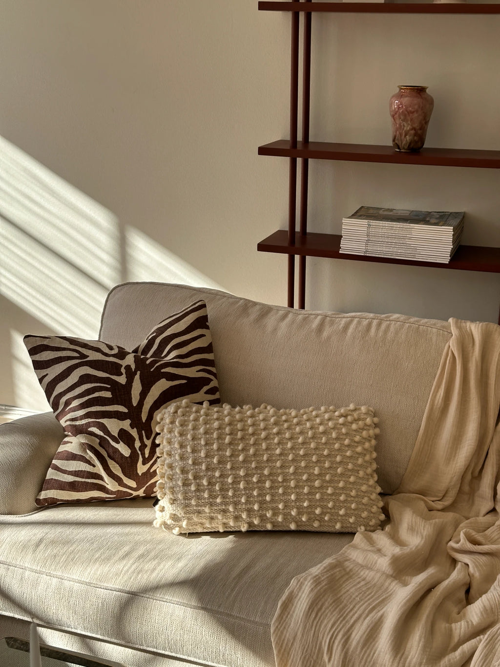 Tinted Objects Tuhlin Throw Pillow, a rectangular cream-colored accent cushion with a textured bobble knit design. This stylish, cozy pillow is perfect for adding comfort and bohemian charm to a modern living room or bedroom.