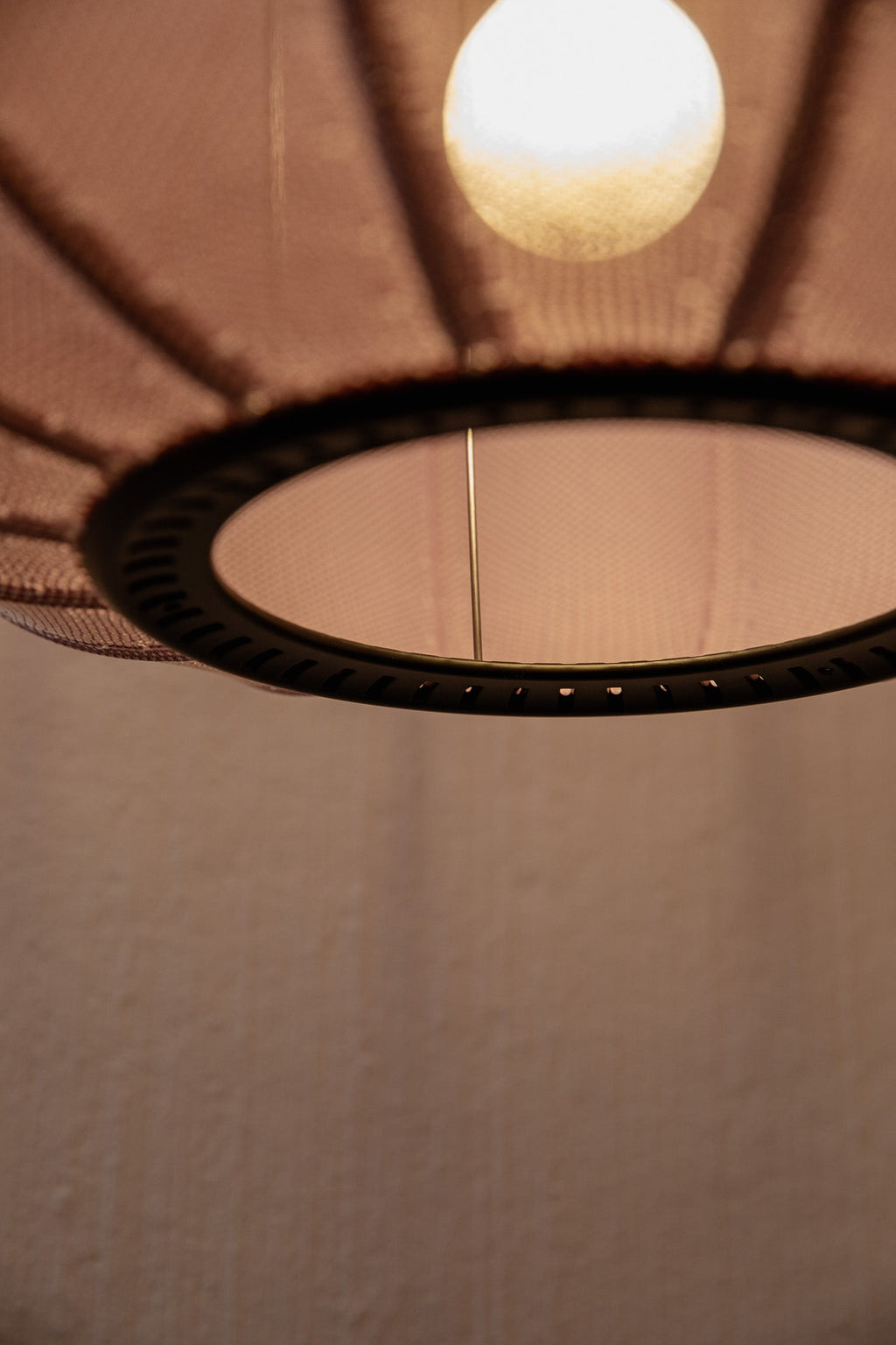 Made by Hand Knit-Wit Ø45 Oval Pendant Lamp, a modern Scandinavian pendant light featuring a soft, finely knitted textile shade in a warm, muted rose color with a distinctive ribbed texture. This contemporary ceiling lamp showcases an elegant oval form and a dark perforated metal frame. Ideal for creating cozy ambient lighting in a minimalist living room, modern dining area, or serene bedroom.