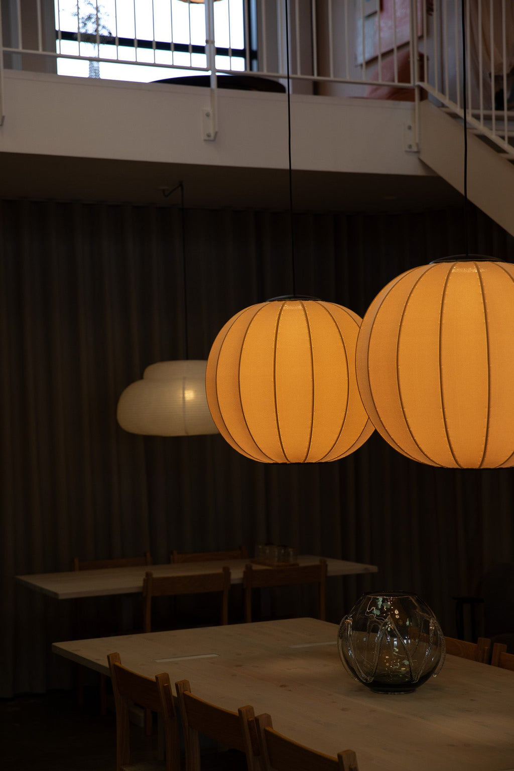 Made by Hand Knit-Wit Ø60 Round Pendant Lamp, a modern Scandinavian ceiling light featuring a spherical knitted fabric shade in a warm orange hue with a distinctive ribbed texture. This contemporary pendant lamp provides soft, ambient illumination, perfect for elegant dining room lighting, a cozy living room, or sophisticated restaurant interiors.