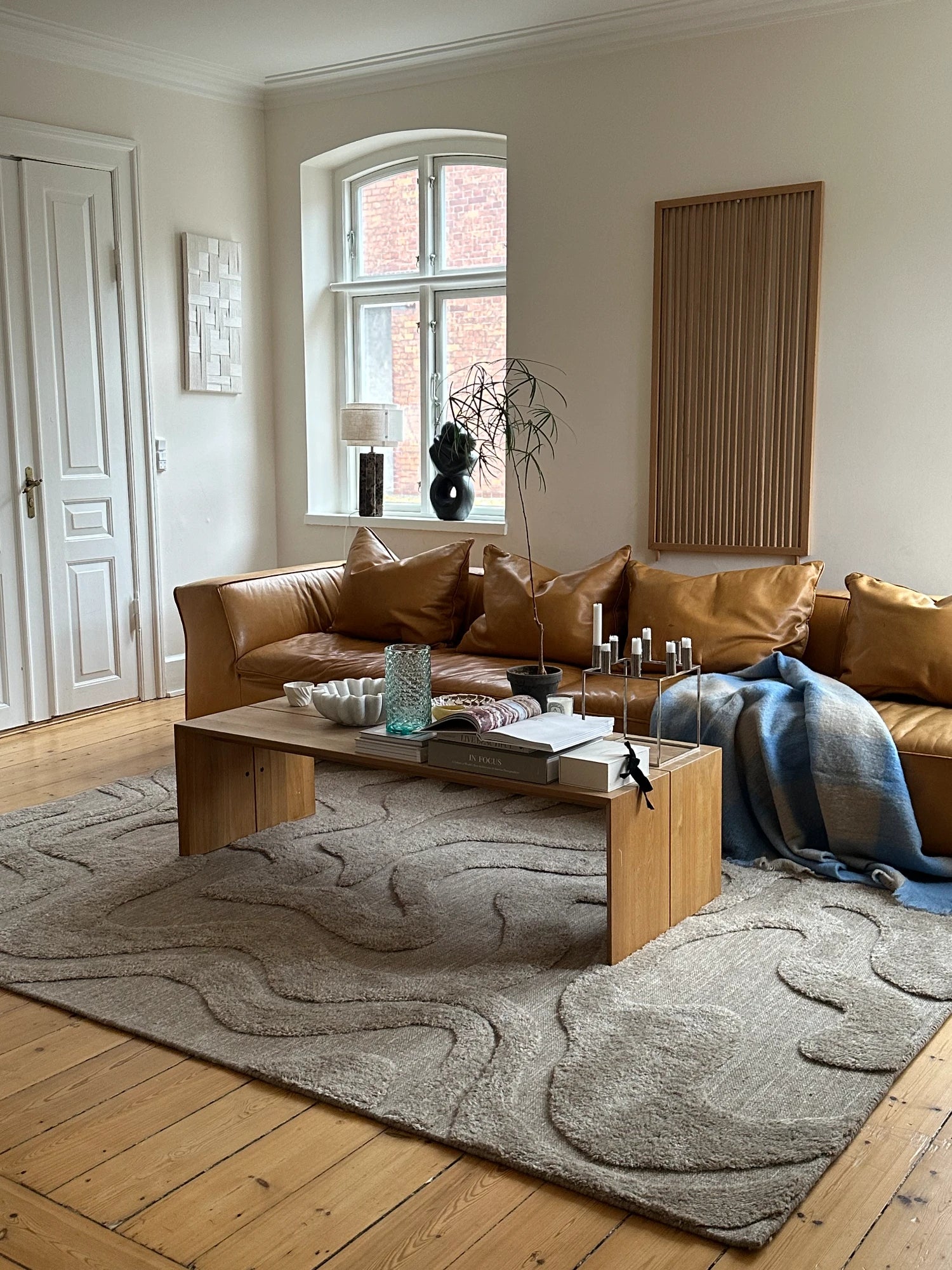 Tinted Objects Norlander Wool Rug, a plush, textured light gray area rug with an abstract, organic wavy relief pattern. This stylish and soft floor covering is perfect for adding warmth and modern design to contemporary living spaces.