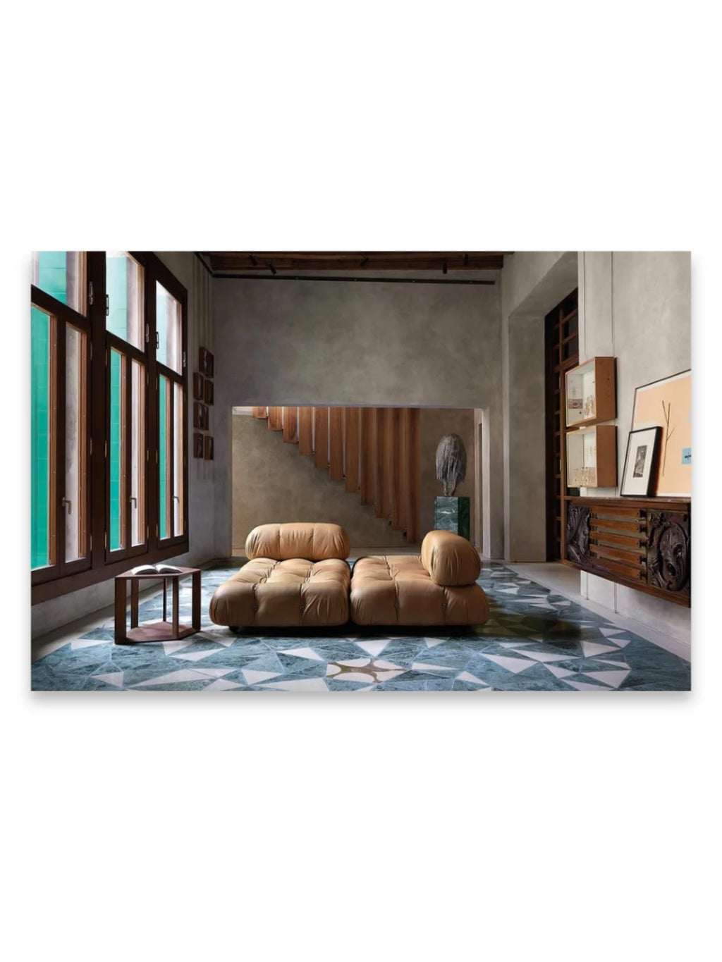 Book In Focus, a captivating lifestyle image showcasing a luxurious living space with a tan tufted leather sofa, a geometric teal and white tiled floor, and dark wood-framed windows. This image is perfect for interior design enthusiasts seeking inspiration for elegant, modern living room decor.
