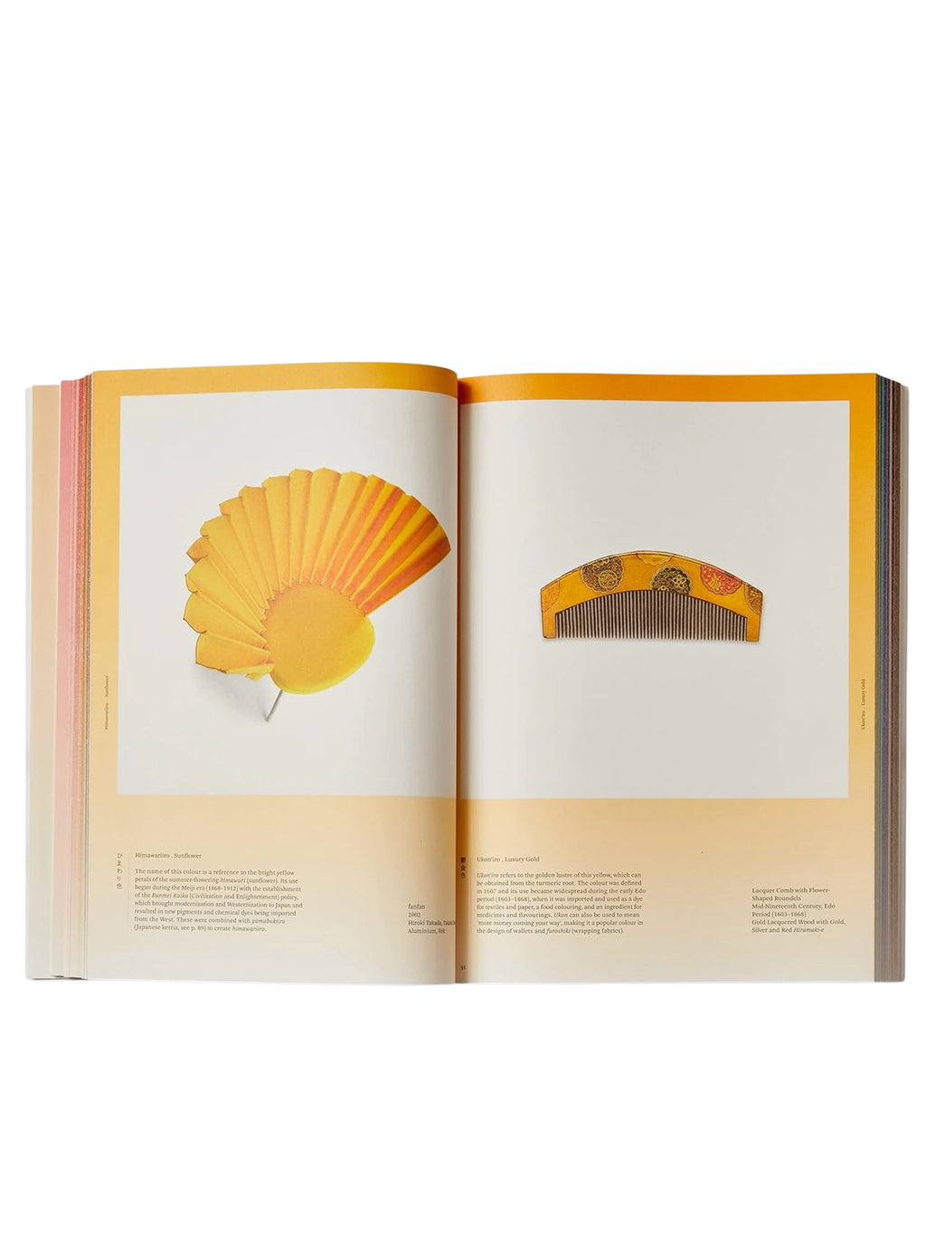 Book Iro - The Essence of Color in Japanese Design, showcasing an open spread with vibrant yellow and orange Japanese artifacts. This art and design book features a pleated yellow fan and a gold lacquered comb with intricate floral patterns, illustrating traditional Japanese aesthetics. An ideal coffee table book for art historians, cultural enthusiasts, and design students.