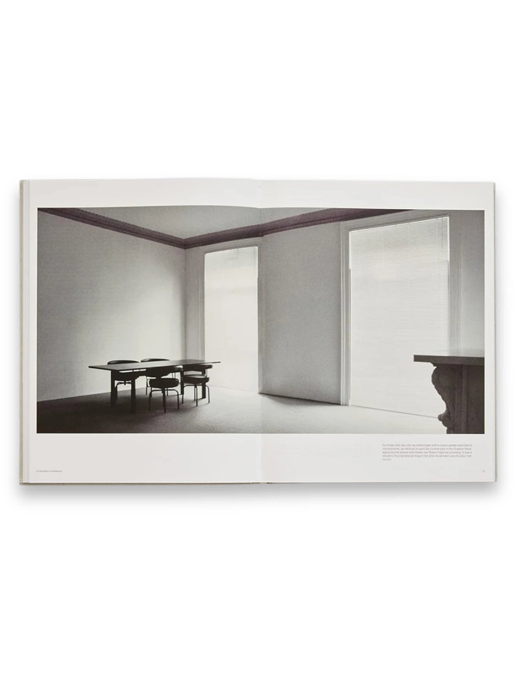 Book John Pawson - Making Life Simpler, an open book displaying a minimalist interior photograph in black and white. The image shows a spacious room with a dark dining table and chairs, contrasting light walls, and large windows with blinds, embodying modern architectural design. This inspiring architecture book is perfect for design enthusiasts, students, and professionals seeking minimalist aesthetic ideas and creative inspiration.