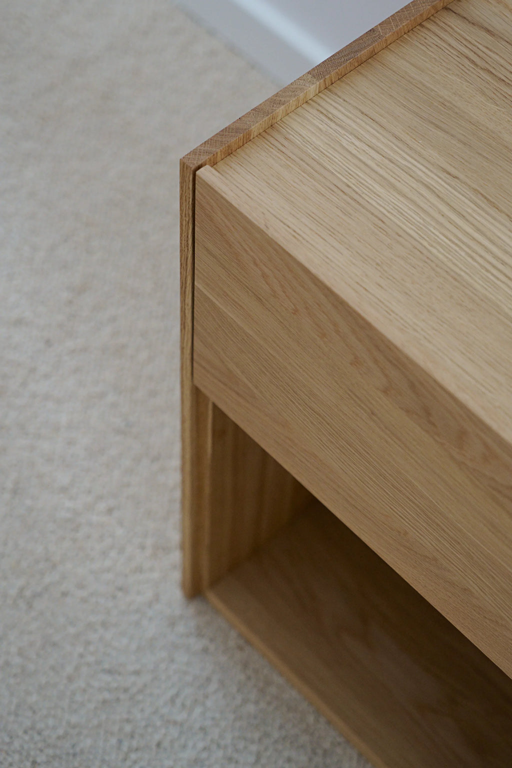 TAMO Kari Nightstand: Close-up of modern light oak wood with visible grain, featuring a single recessed drawer and an open shelf. A premium, minimalist design perfect for bedroom storage.