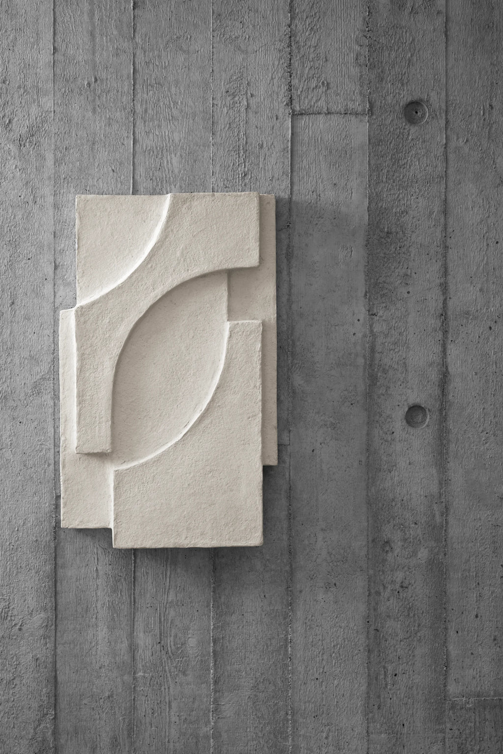 Kristina Dam Serif Relief M, a brutalist-inspired fiber concrete relief wall art in a natural off-white beige, featuring a textured, sculptural surface with layered abstract geometric shapes. This minimalist design creates a striking 3D effect, perfect for contemporary gallery walls or modern living rooms seeking an organic modern aesthetic.