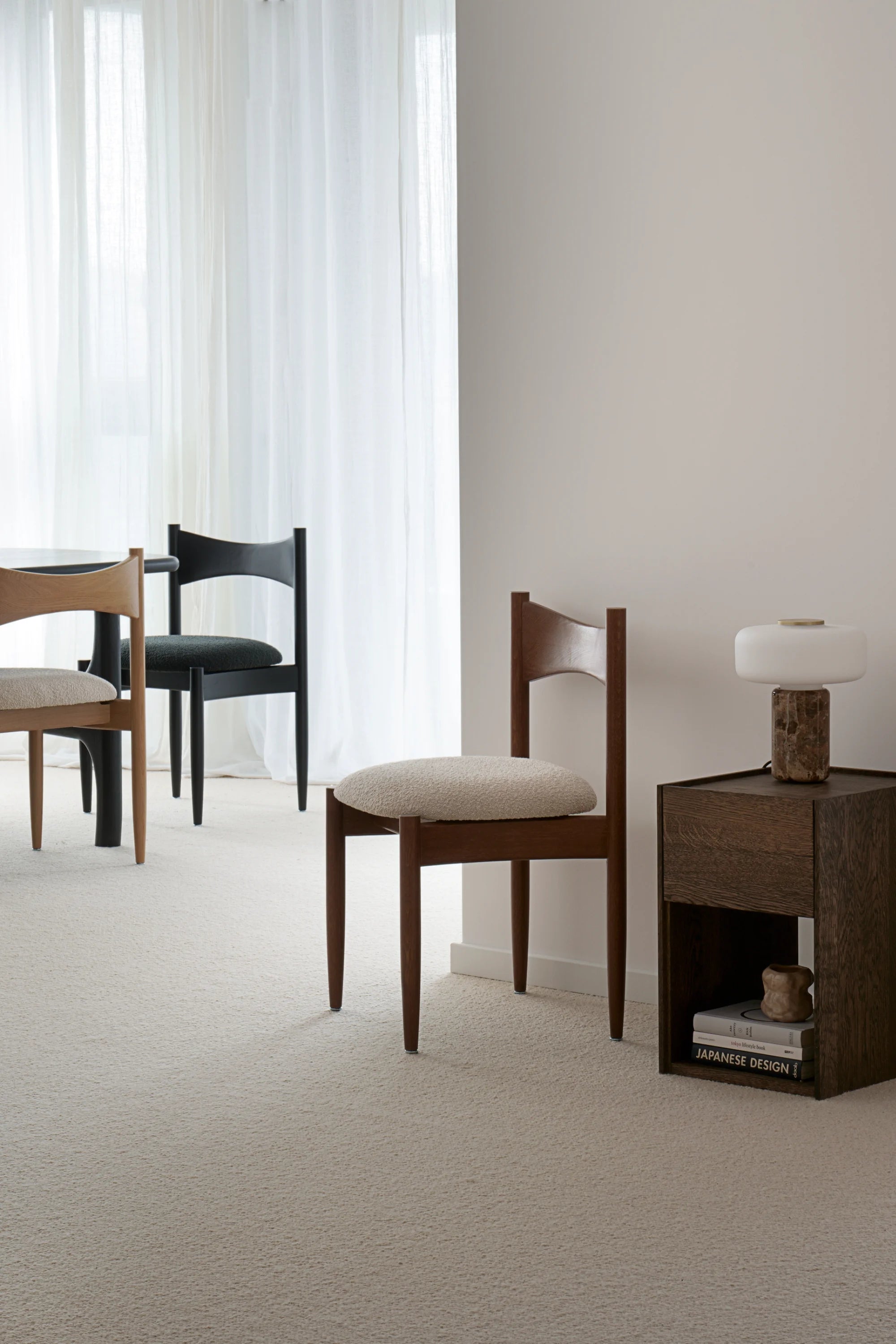 Dining room with wooden chairs and a side table against a neutral wall.
