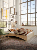 the orbit bed karup design in a loft style minimalistic apartment with artprints on the wall and a lounge chair next to the bed