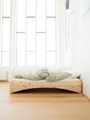 the orbit bed karup design in a minimalistic apartment that has tall white walls and big windows that bring alot of natural light into the room