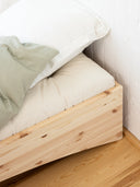 close up photo of the orbit bed by karup design, the photo features a wooden bed frame, a white mattress with a blanket on it and white pillow