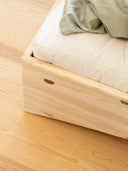 close up photo of the orbit bed by karup design, the photo features a wooden bed frame, a white mattress with a blanket on it