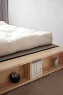Wooden platform bed with storage shelves and a mattress on a plain background
