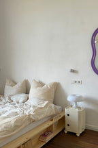 Bedroom with wooden bed, white pillows, and a nightstand with a lamp.