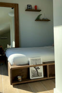 Bedroom with wooden bed frame, shelves, and decor items.