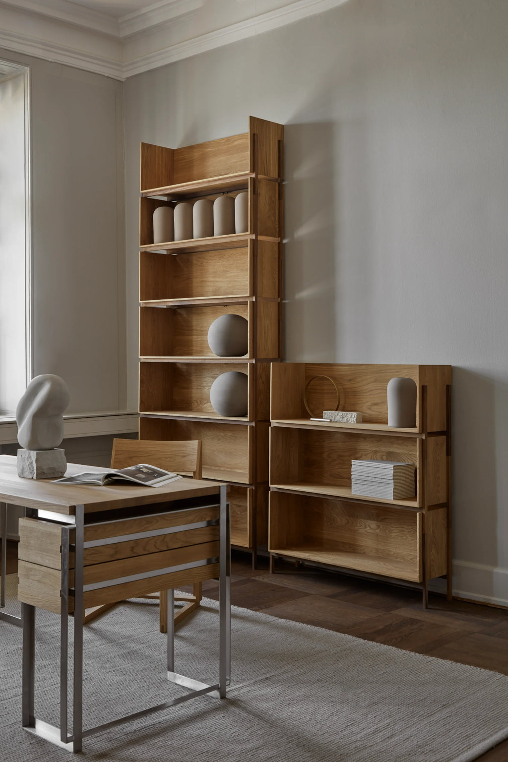Kristina Dam Outline Desk, a modern minimalist desk crafted from natural solid oak wood with a distinctive integrated drawer unit and a sleek matte brushed stainless steel frame. This Scandinavian-inspired writing desk features clean lines and a contemporary design, offering stylish storage for a home office or creative workspace.