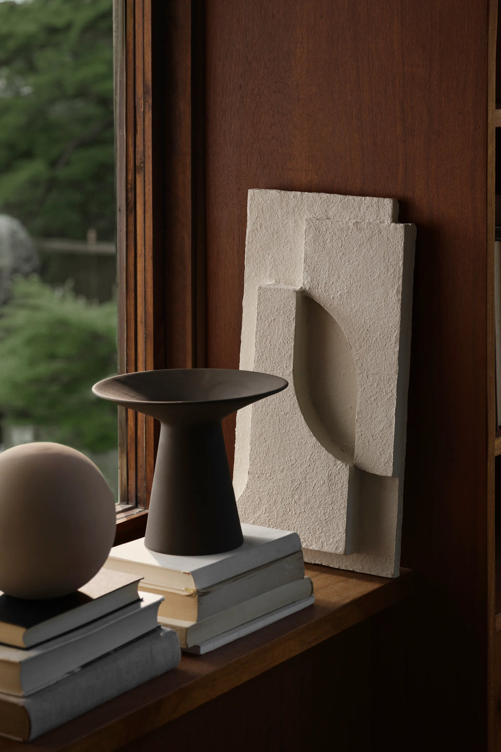 Kristina Dam Serif Relief S, a sculptural off-white wall art piece crafted from textured cast stone with a rough, porous finish, featuring a minimalist geometric relief design including a prominent curved arch and layered rectangular forms. This contemporary architectural art is perfect for modern shelf styling or as a striking Brutalist-inspired accent for living rooms and organic modern interiors.