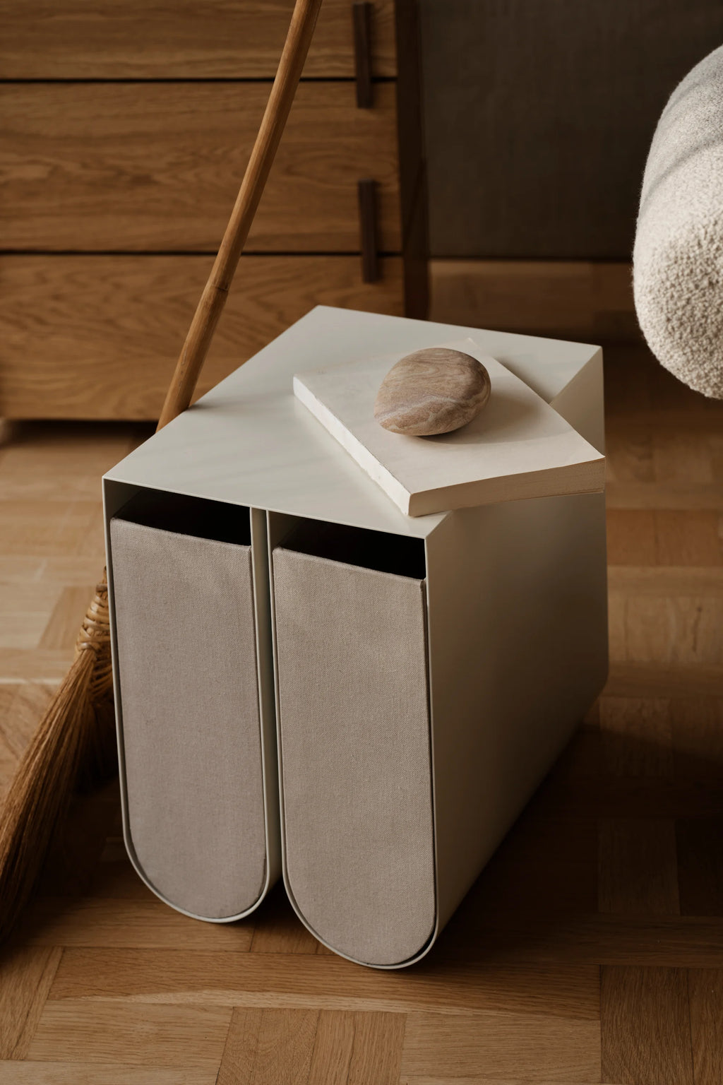 Kristina Dam Curved Side Table, a modern minimalist side table crafted from matte beige powder-coated steel featuring two integrated light grey fabric storage bins with elegantly curved fronts. This Scandinavian design offers practical storage and a clean aesthetic with its subtle color palette. Perfect as a contemporary nightstand for bedrooms or a stylish accent table for living rooms and entryways.