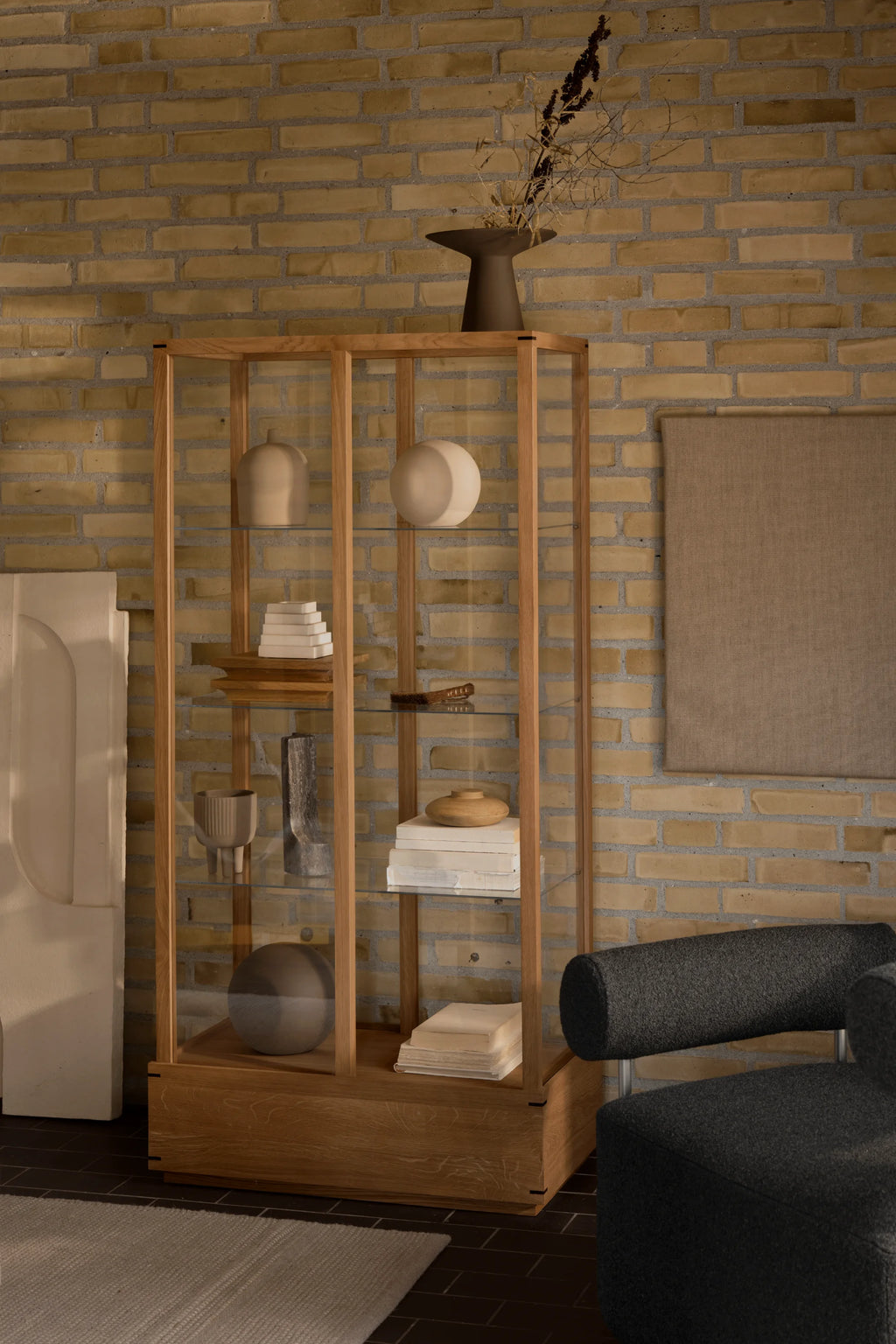 Kristina Dam Japanese Cabinet L, a tall, elegant display cabinet featuring a minimalist solid oak wood frame and base with transparent clear glass panels and interior shelves.